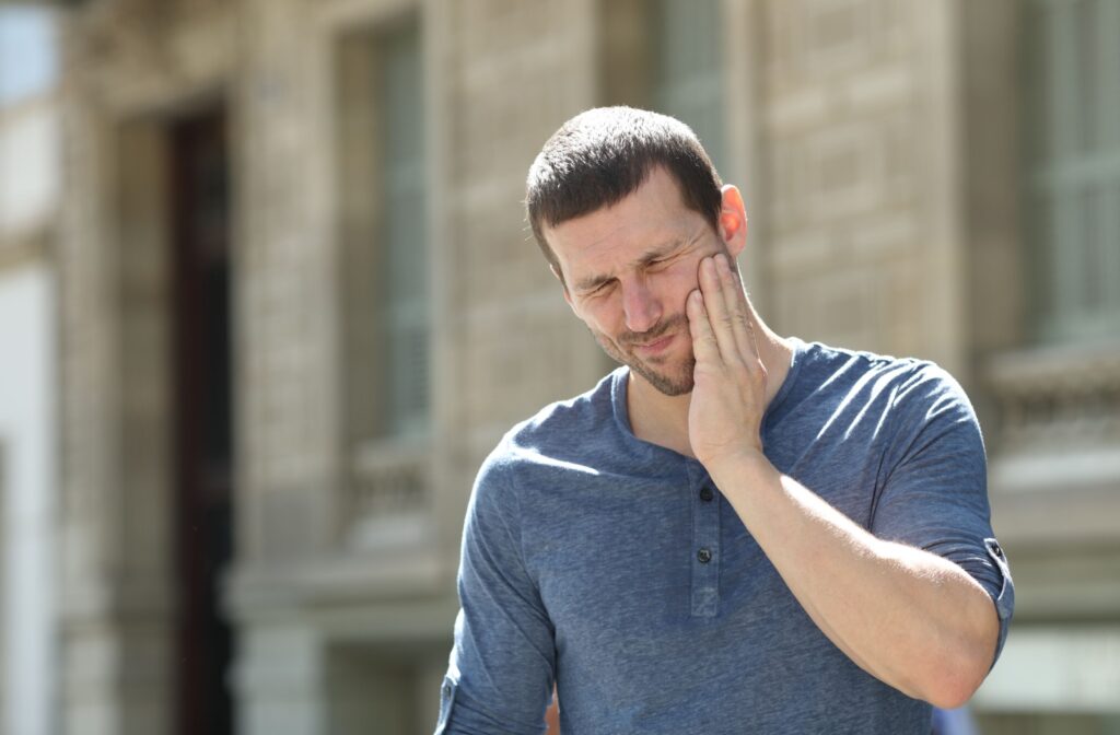 A man suffering from a toothache holds his right cheek with his right hand.