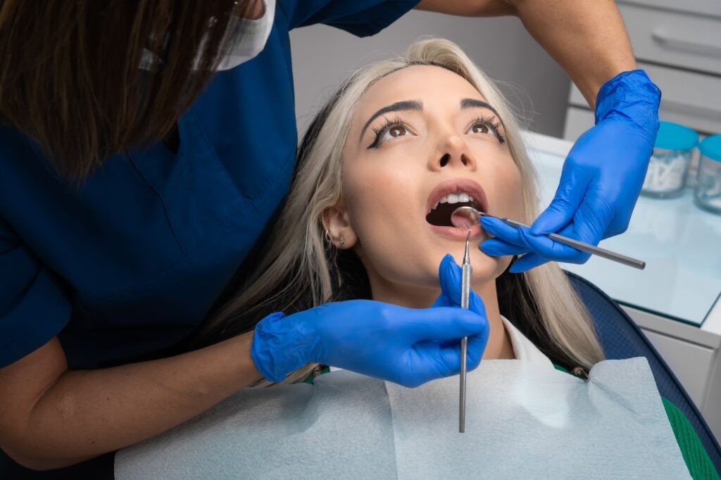 A close-up picture of a dentist examining a woman's teeth for signs of cavities or tooth decay.