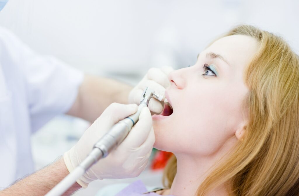 A close-up image of a woman getting her teeth professionally cleaned by a dental hygienist.