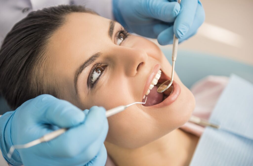 A close-up image of a dentist performing a thorough examination of an adult patient's mouth, looking for signs of chipped or cracked teeth that are causing discomfort.