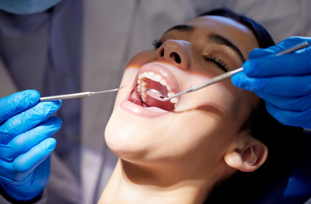 A person receives a professional dental cleaning from a dentist wearing blue gloves.
