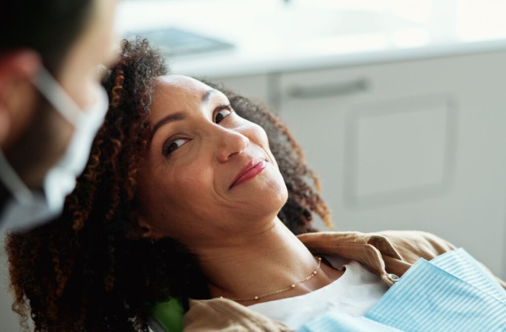 A person smiling while reclining in a dental chair, looking reassured during a dental visit.