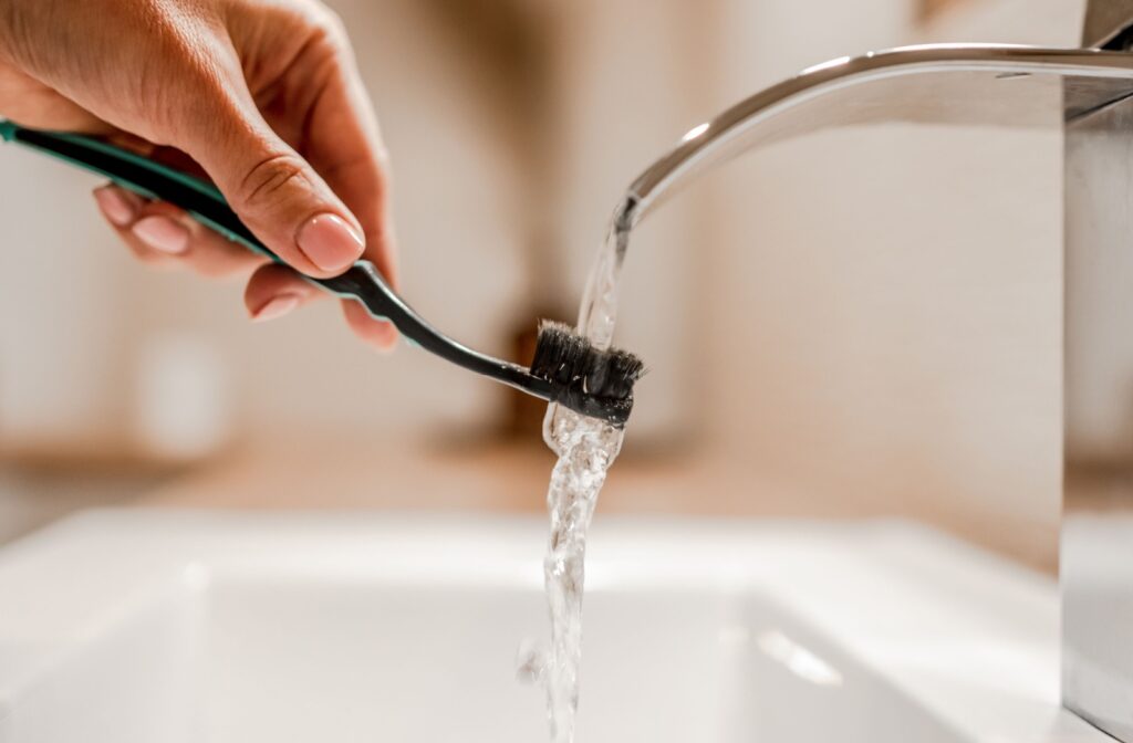 A close-up image of someone thoroughly rinsing their toothbrush after brushing their teeth.