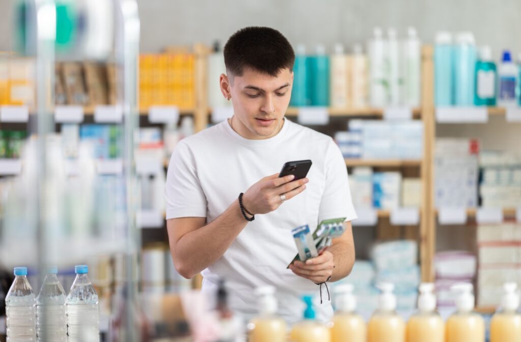 A young adult looks up information about toothbrushes on their phone to decide which one to buy.
