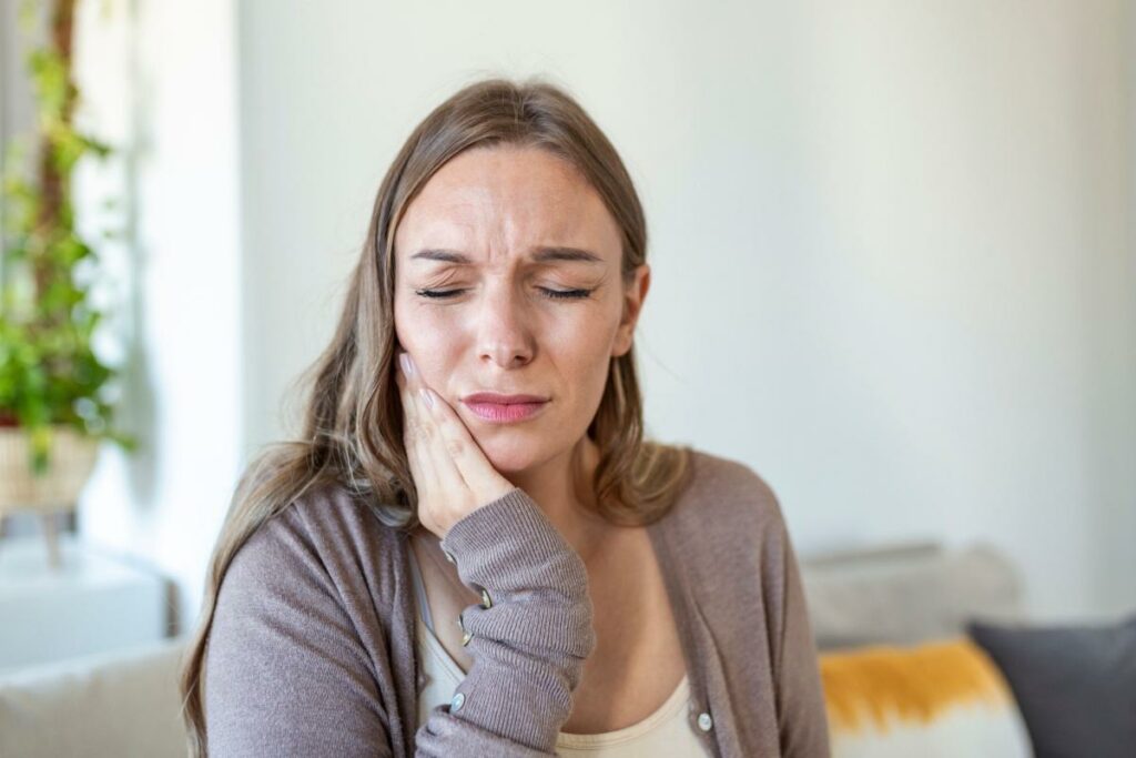 Woman holding her right jaw out of pain.
